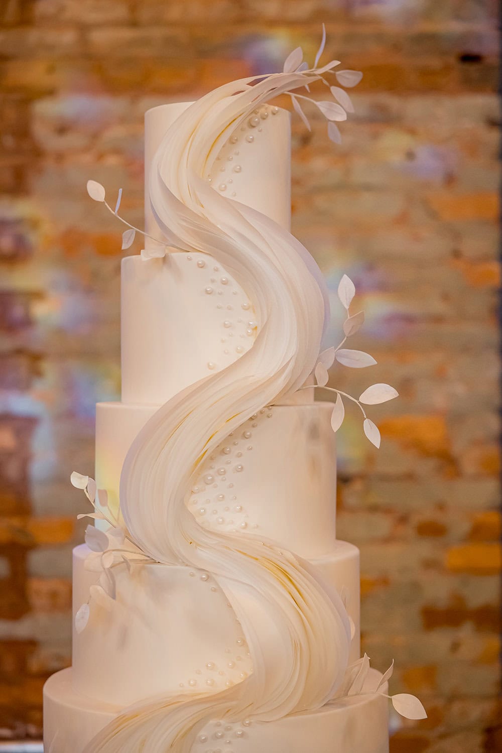 Wedding cake with flowing white fondant and delicate floral accents.