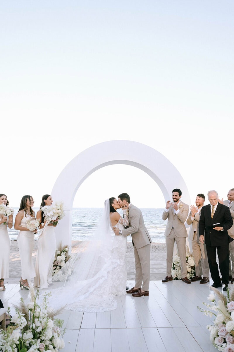 Beach wedding ceremony with ocean view, floral arrangements, and a romantic arch.