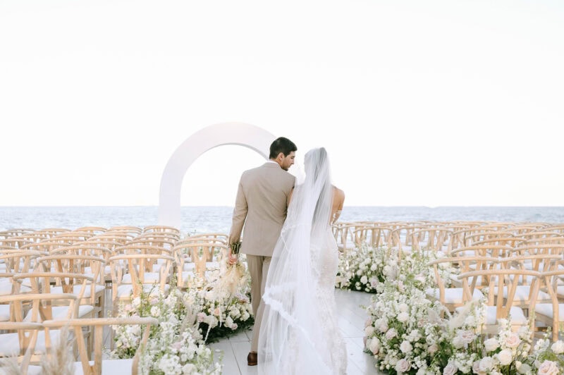 Wedding ceremony on the beach with floral arrangements and ocean view backdrop.