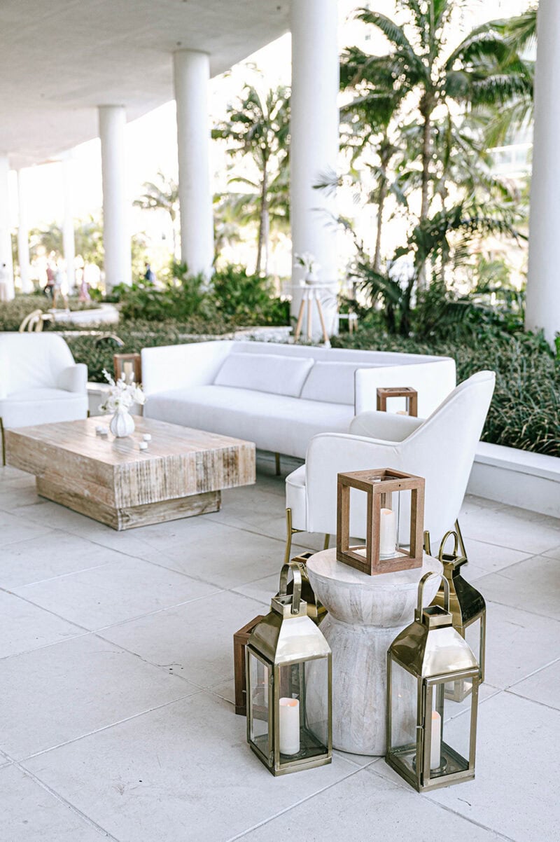 Outdoor lounge with white sofas, wooden table, and lantern decor.