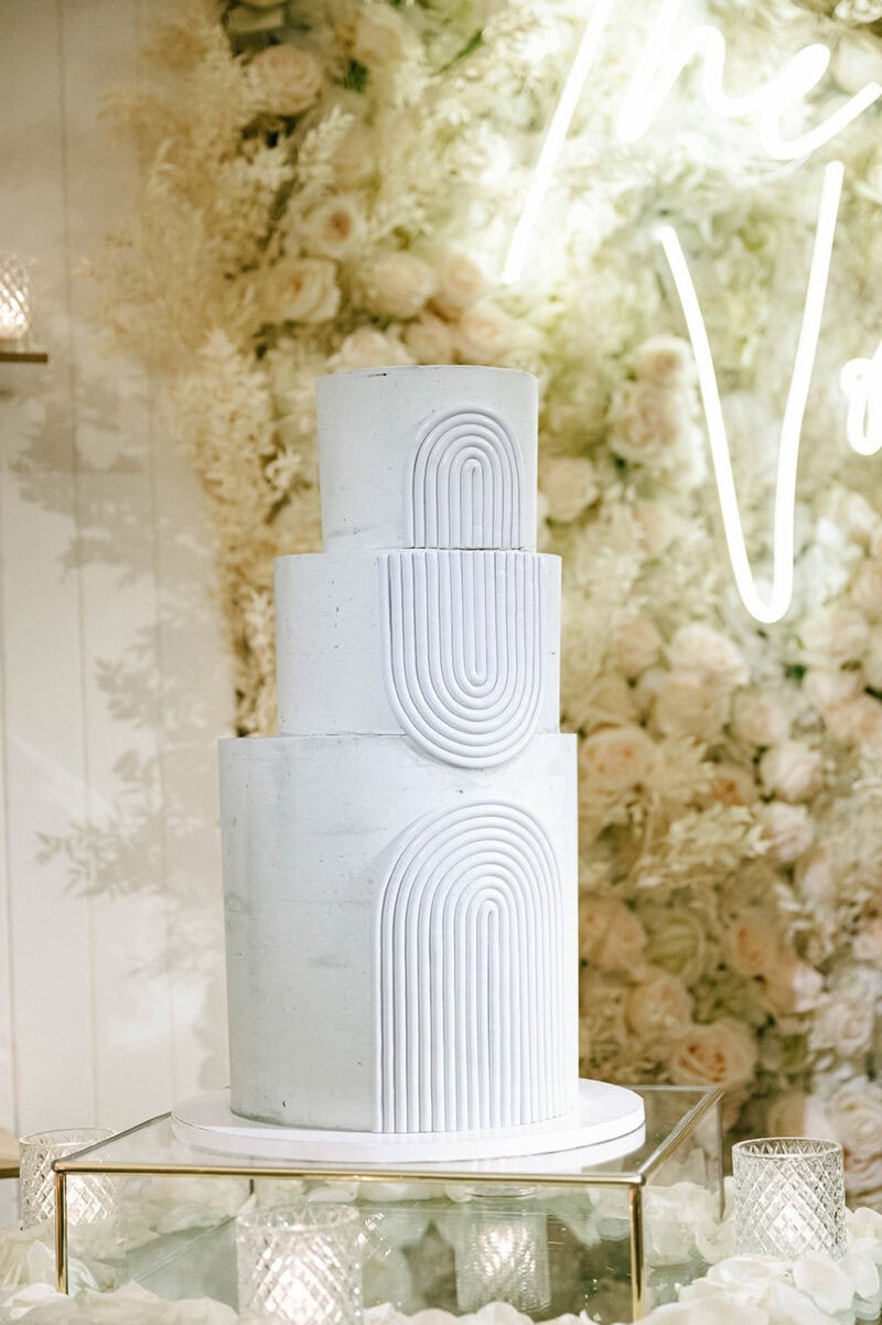 Wedding cake with minimalist white tiers and geometric patterns.
