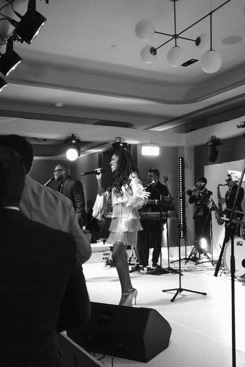 Performing artist singing on stage with band and instruments.