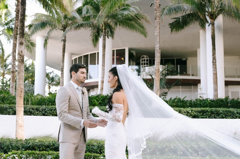 Bride and groom exchanging vows in a tropical outdoor setting.