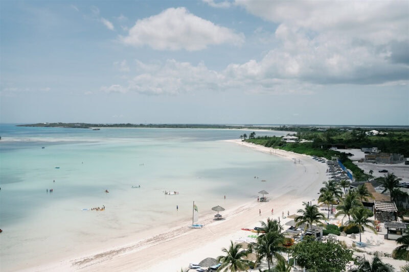 Beach wedding ceremony on a sunny day with turquoise waters and palm trees.