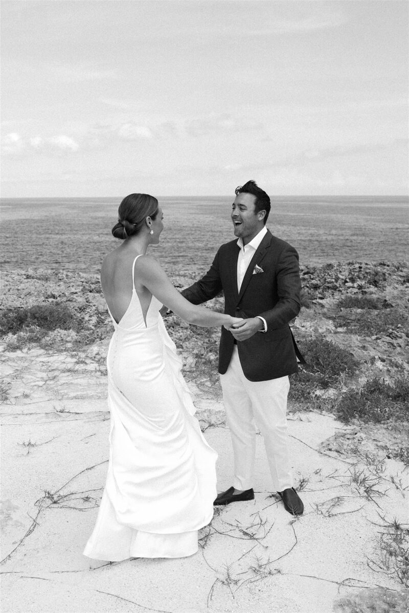 Bride and groom holding hands during their seaside wedding ceremony.