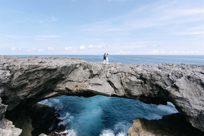 Babbie and Jamie standing on a coastal rock formation overlooking the ocean.