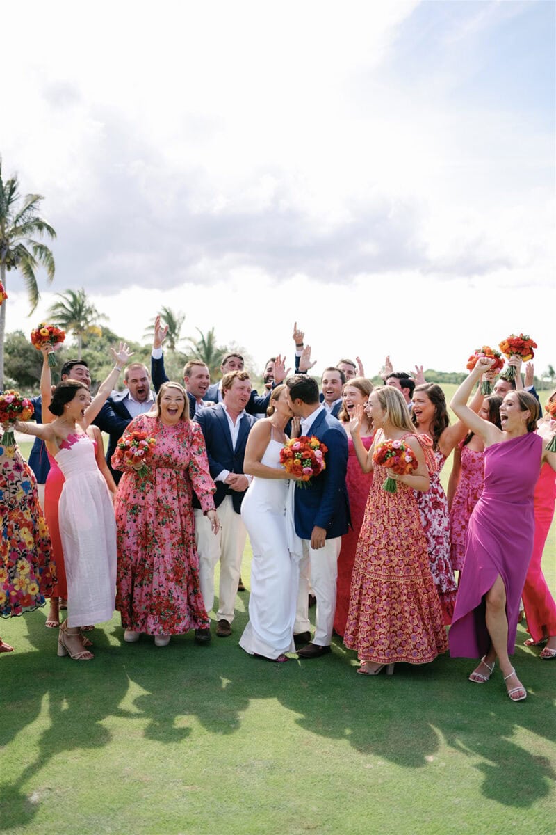 Wedding guests celebrating outdoors with joyful dancing and laughter.