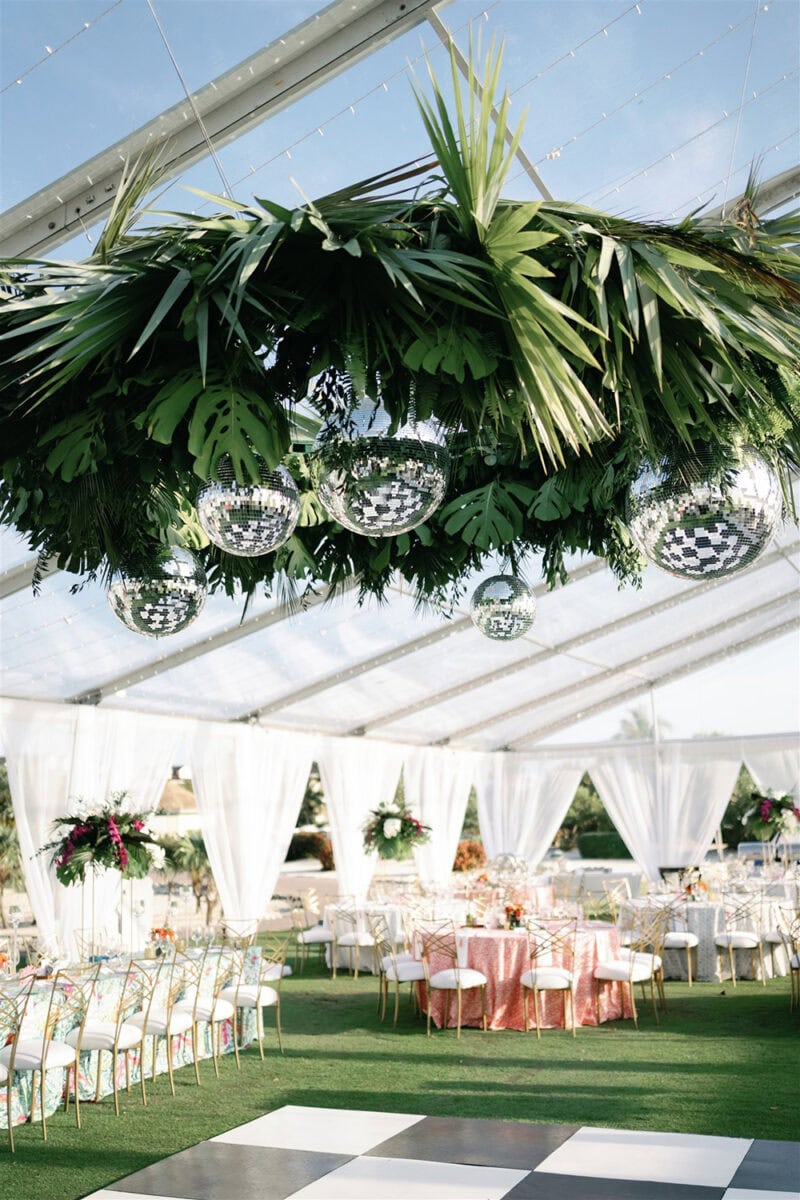 Beautiful tropical-themed wedding reception with lush greenery and mirrored disco balls.