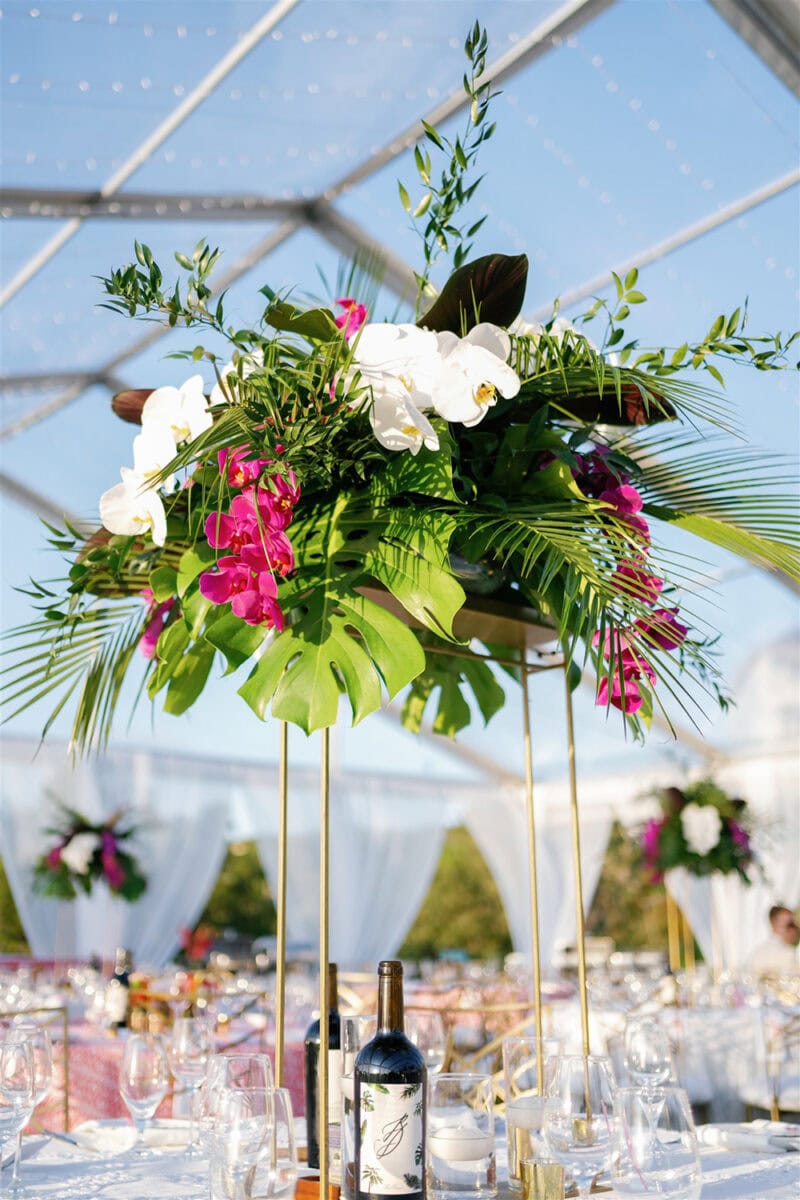 Floral centerpiece with white orchids, pink flowers, and lush greenery at a wedding.