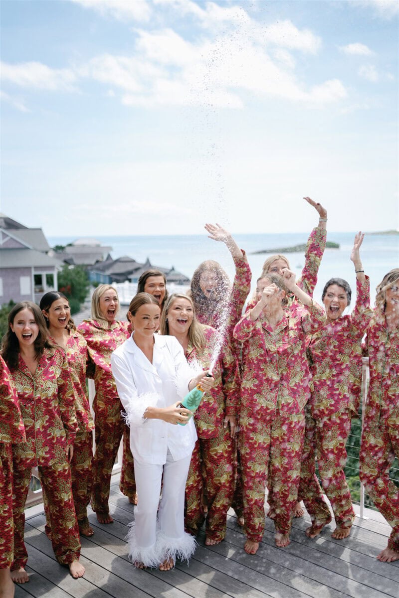 Group of women in floral pajamas celebrating outdoors by the water.