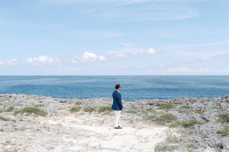 Elegant groom standing by the ocean at a wedding event.