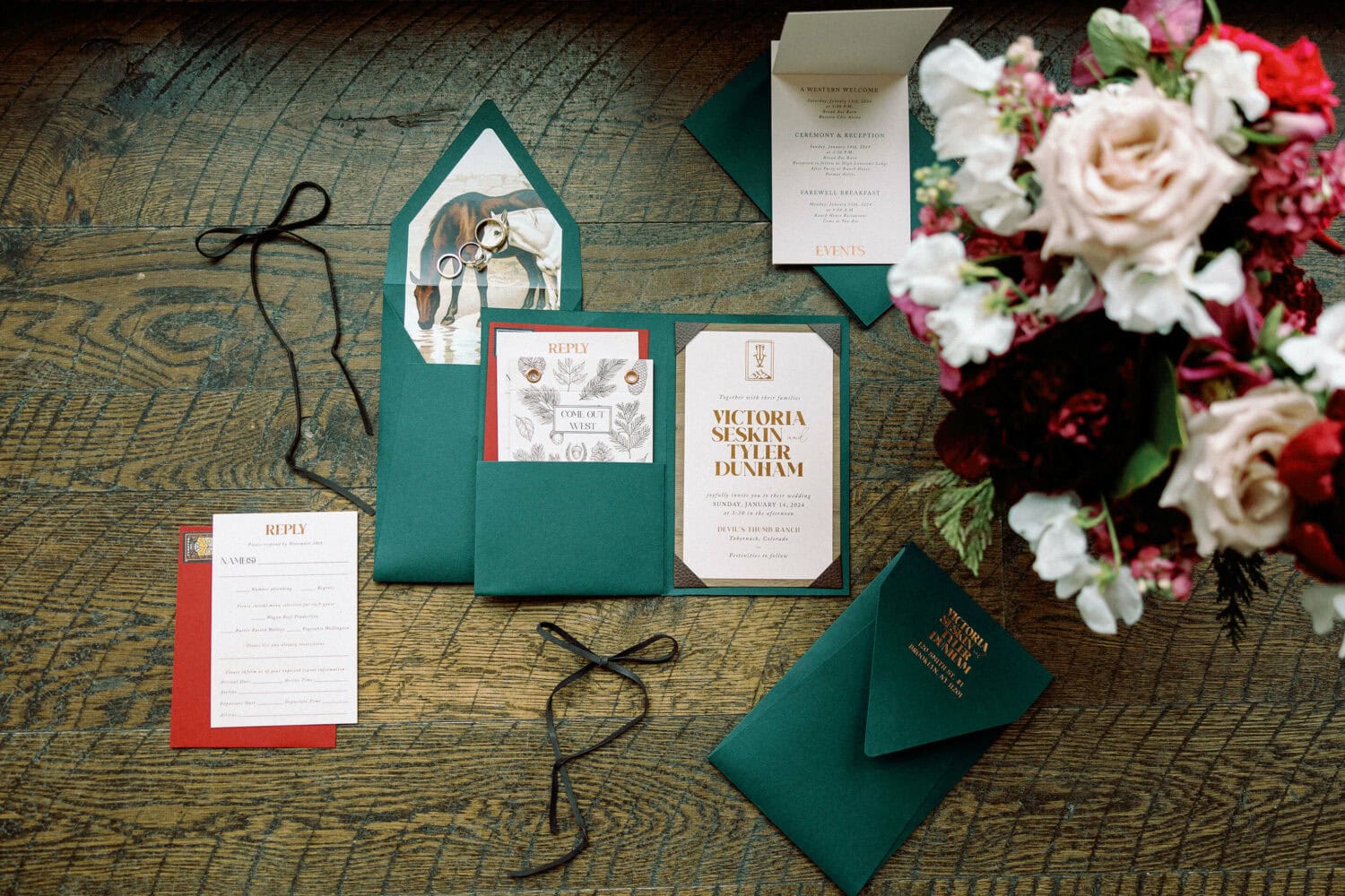 Wedding invitation suite with floral accents and stationery on rustic wooden table.