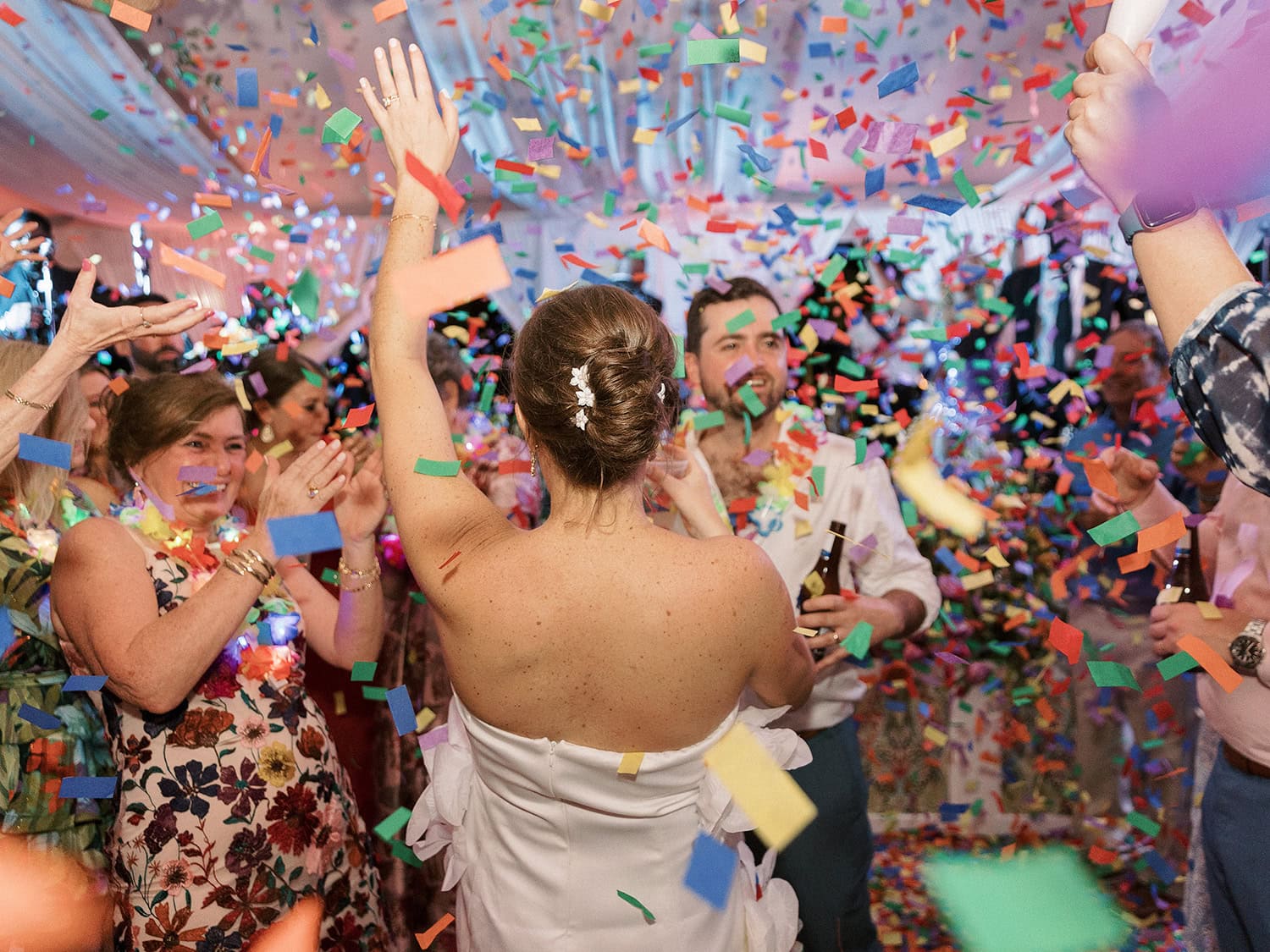 A bride and guests celebrating with confetti and joyful expressions at a wedding reception.