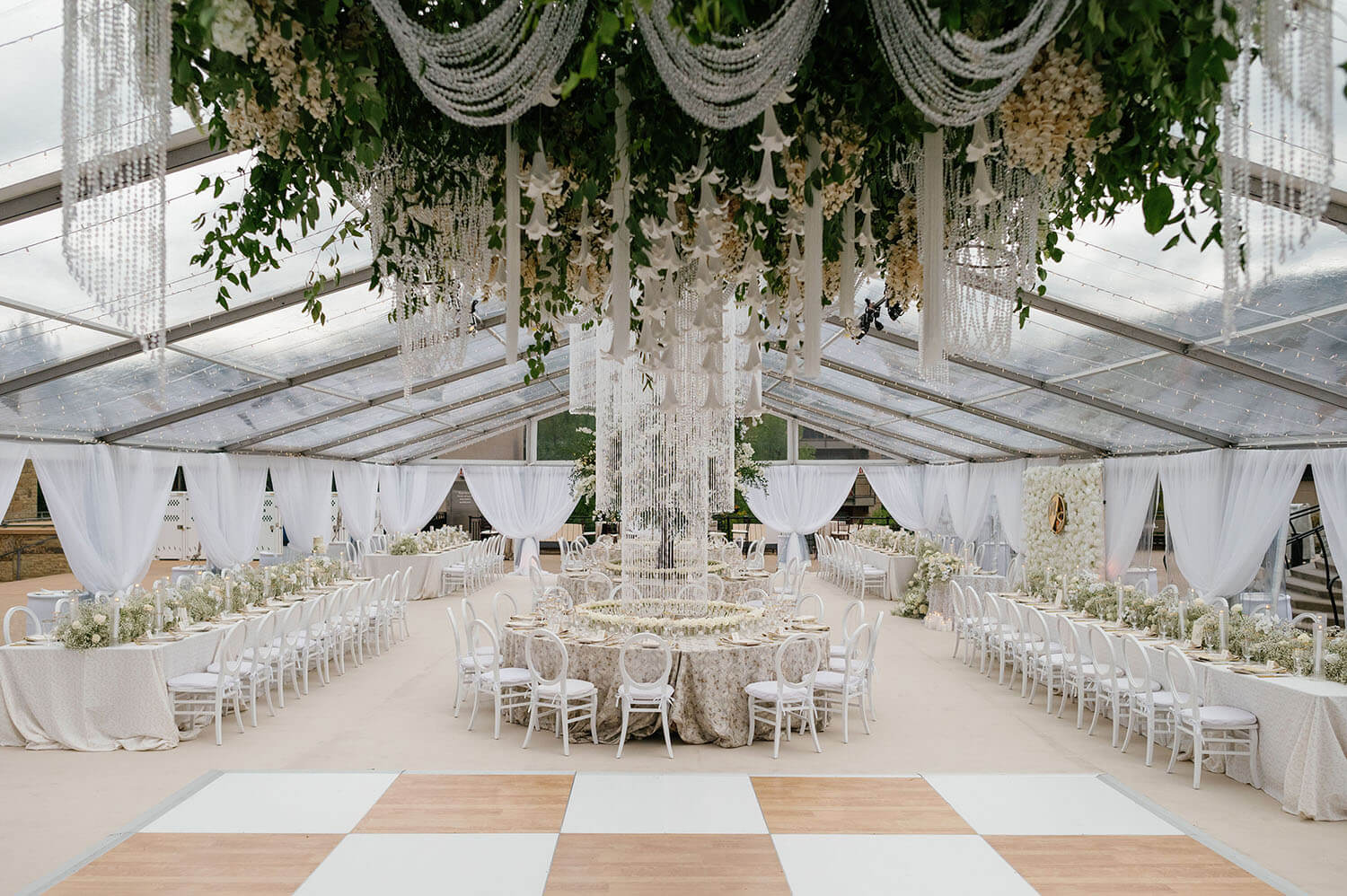 Elegant wedding reception with floral arrangements and draped fabric ceiling decor.