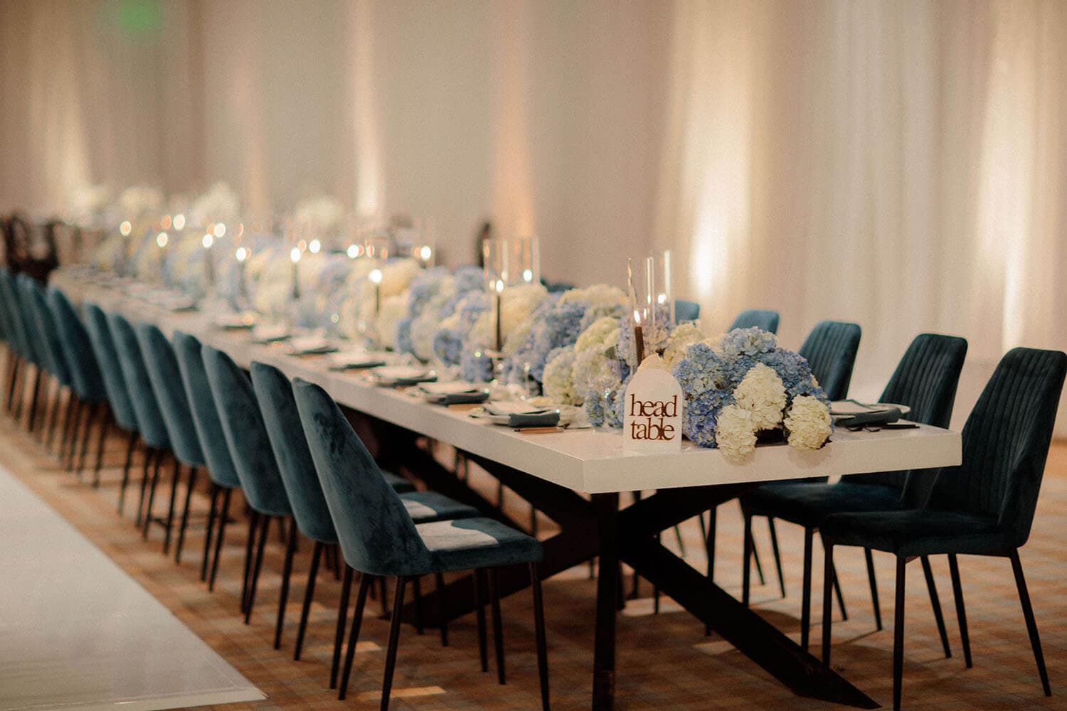 Elegant wedding reception table with floral centerpieces and place settings.