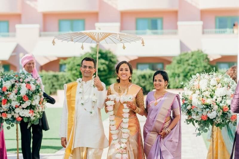 Wedding procession with bride, groom, and family members outdoors.