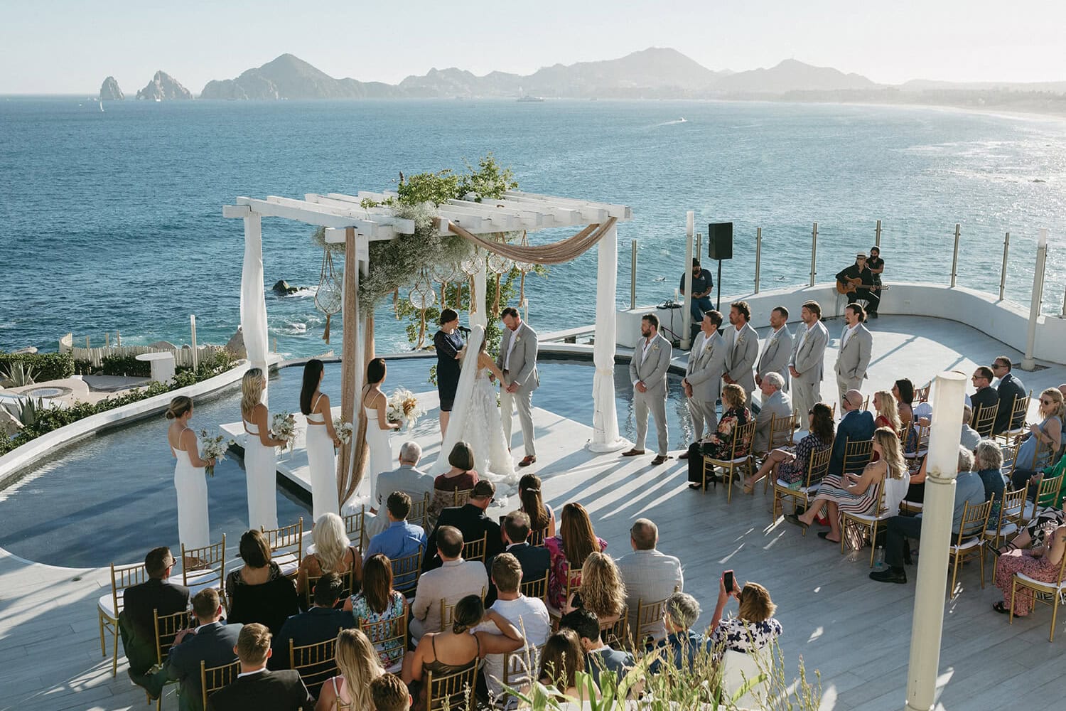 Elegant outdoor wedding setup with ocean view and floral decorations.