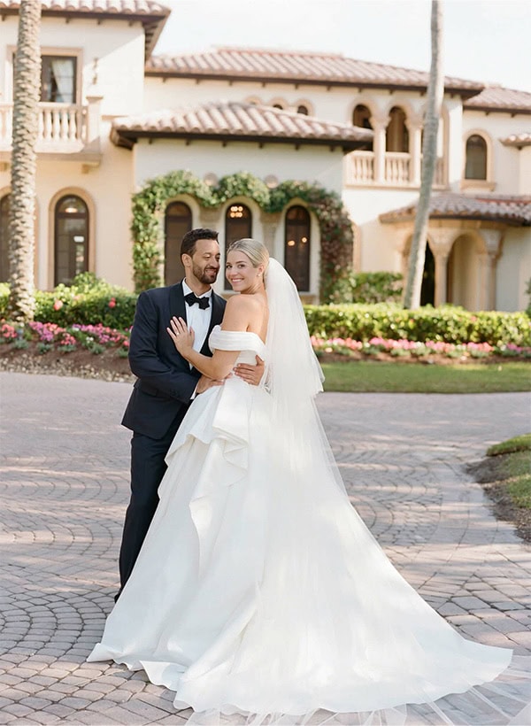 Wedding couple smiling outdoors in front of a beautiful estate.