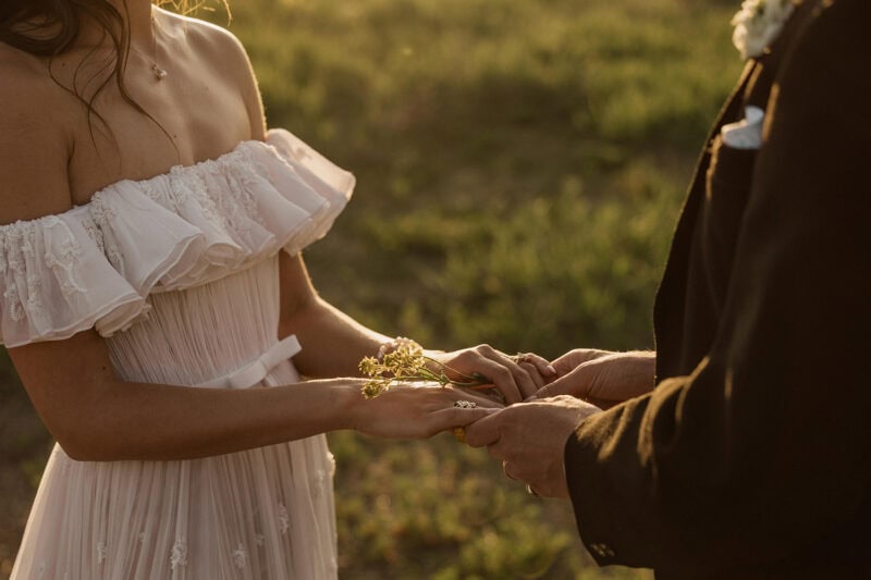Bride and groom exchanging vows outdoors during sunset.