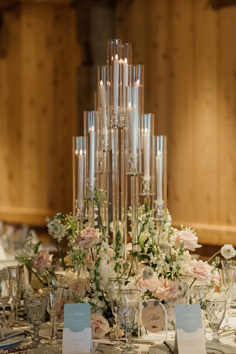 Stunning wedding table decor featuring tall glass candle holders and delicate flowers.
