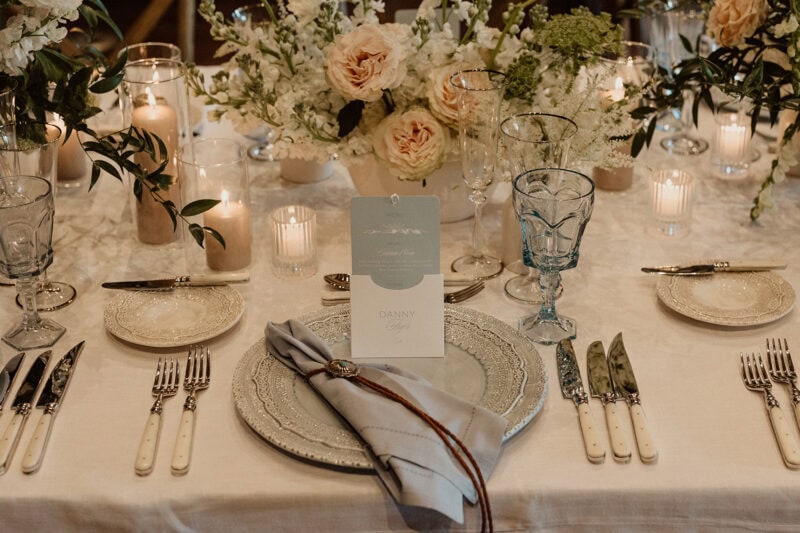 Beautiful wedding table arrangement with flowers, candles, and fine tableware.