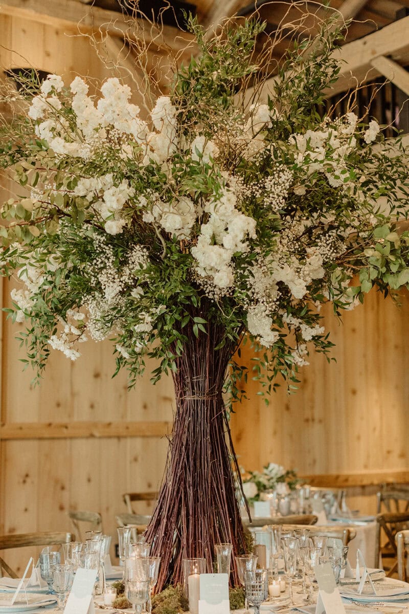 Beautiful white and green floral arrangement in a tall, rustic vase.