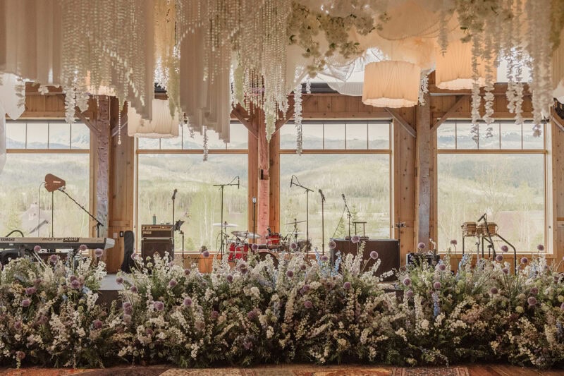 Elegant wedding stage decorated with flowers and hanging floral arrangements, with musical instrumen.