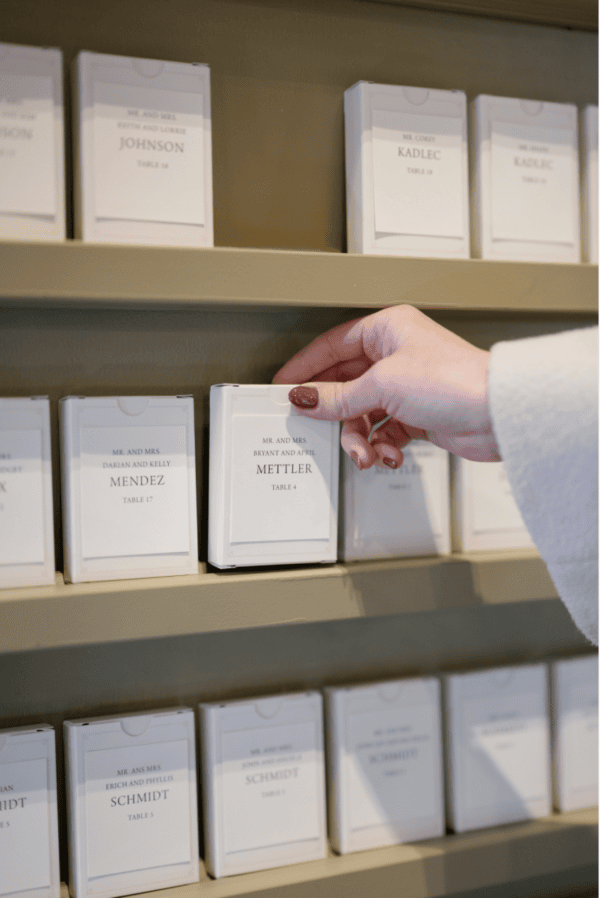Person selecting a wedding place card from a display shelf.